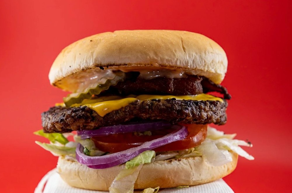 A burger with cheese, bacon and vegetables from Stoopid Burger